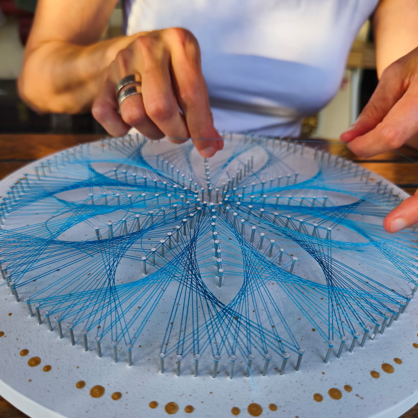 Detall del mandala de fil blau amb els punts daurats